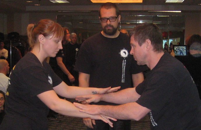 Heavy Spinning Eine Schülerin und ein Schüler beim schweißtreibenden Spinning. Im Hintergrund ist Meister Ashe Higgs und schaut auf die beiden.