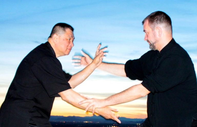 Master Spinning Grandmaster Sam Chin und Master Alex Skalozub beim Spinning Hands. Im Hintergrund ist ein Sonnenuntergang.
