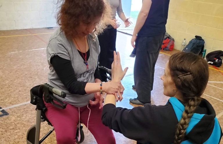 Bewegungsqualitäten Emma und Leefke bei einer Übung in London. Emma sitzt im Rollator und Leefke kniet, für die gemeinsame Höhe.